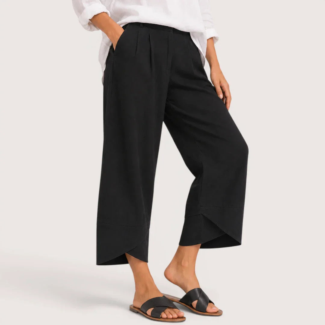 Person wearing black wide-leg pants and a white shirt on a light gray background
