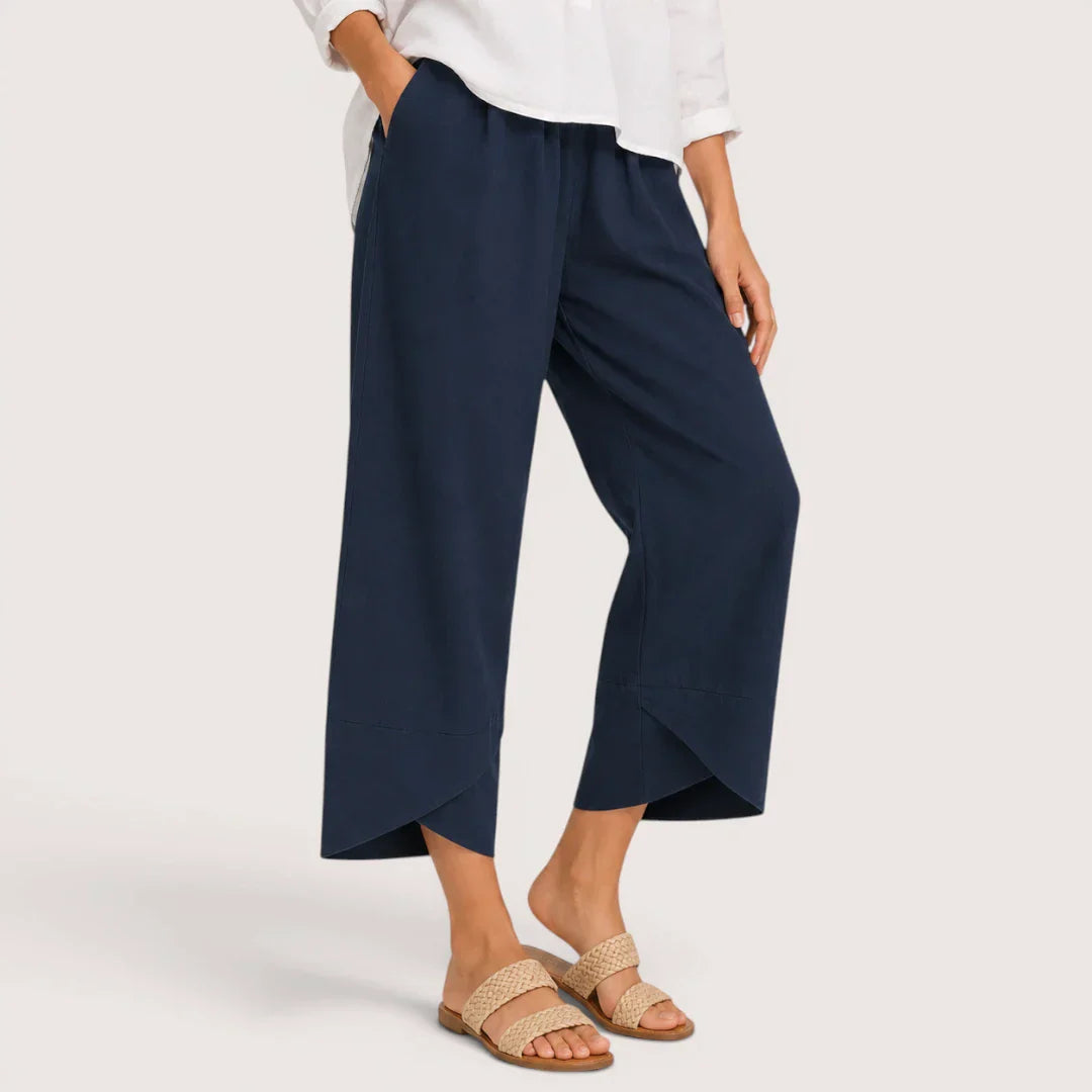 Person wearing navy wide-leg pants and a white top on a light gray background