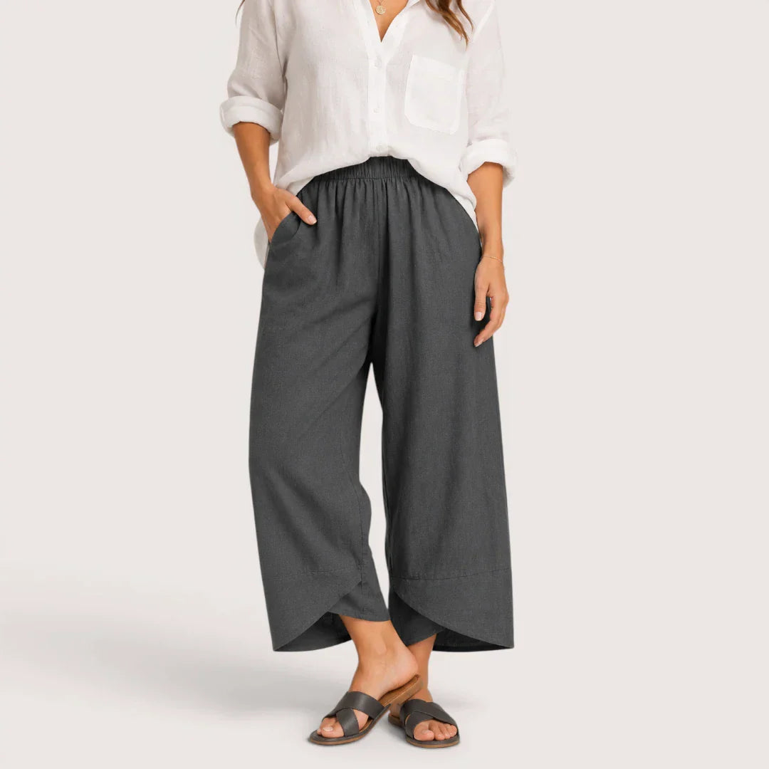 Person wearing gray wide-leg pants and a white shirt on a plain background